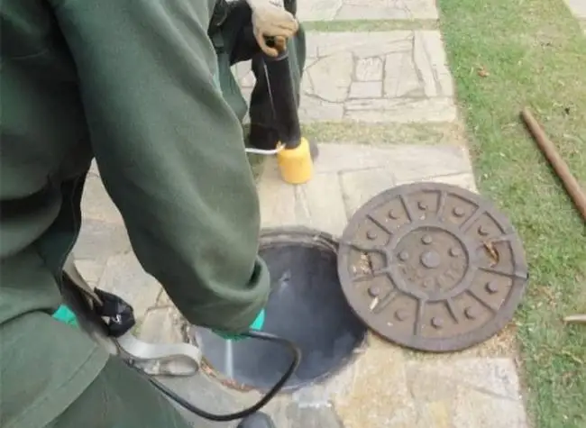 Técnico da Detecta aplicando inseticida em pó em uma caixa de passagem